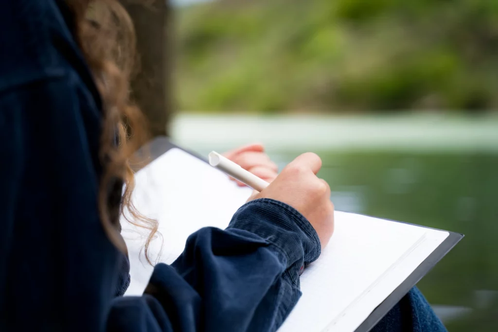 A woman writing in a journal outside.