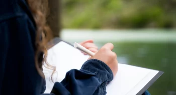 A woman writing in a journal outside.